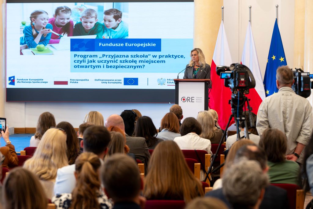 Ministra B. Nowacka przemawiająca przy mównicy, w tle plansza z rzutnika z tytułem konferencji i poglądowym zdjęciem dzieci
